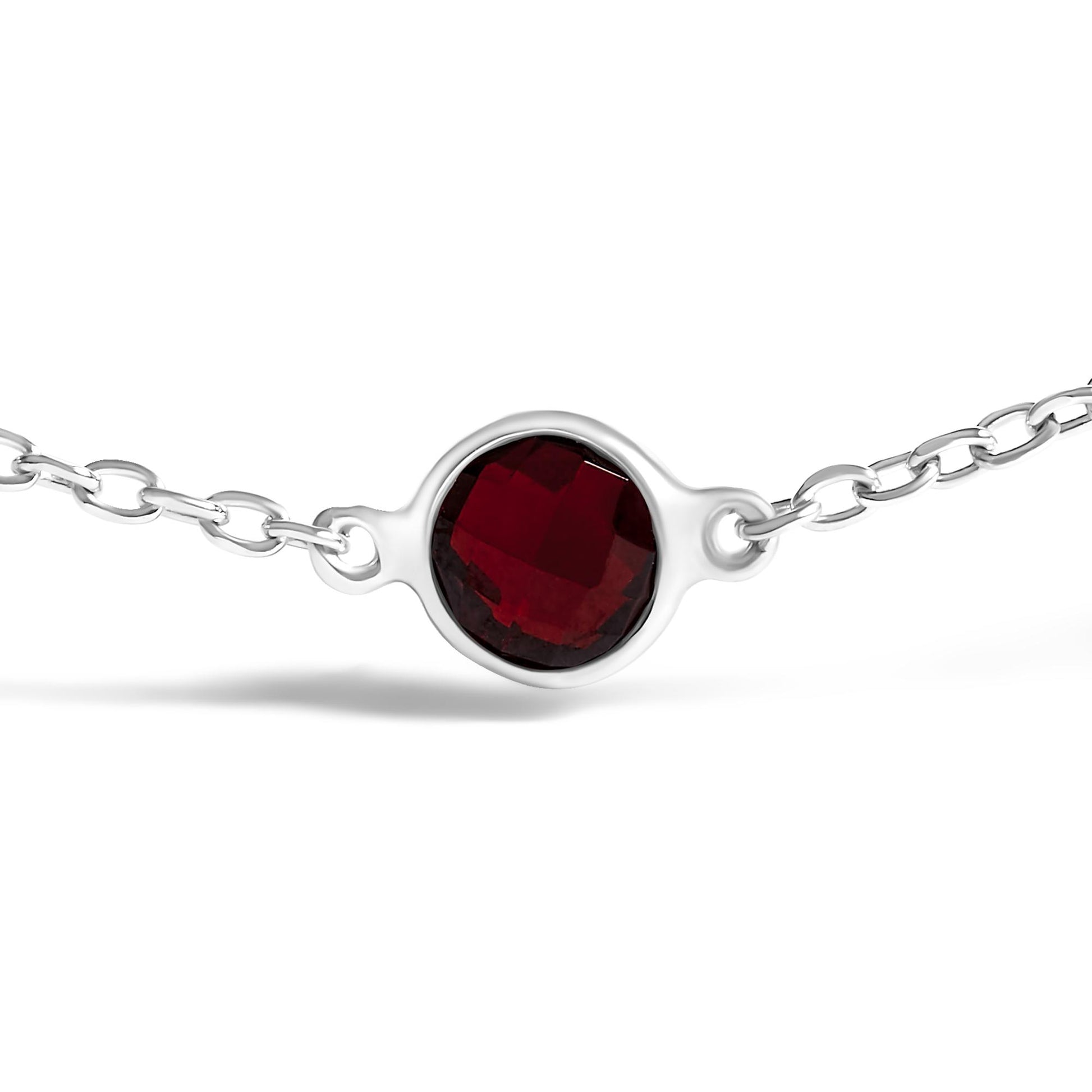 Close-up front view of a white metal bracelet featuring a round red gemstone in bezel setting on a white background.
