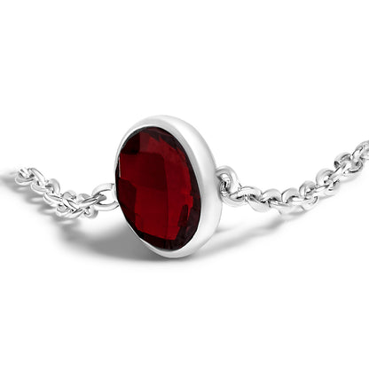 Close-up front angle of a white metal bracelet featuring a single oval-shaped red gemstone in a bezel setting, attached to a delicate chain.