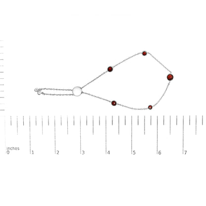 White metal bracelet with round red gemstones in bezel settings, displayed flat on a ruler for size reference, top-down angle.
