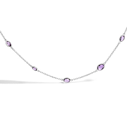 Close-up front angle of a white necklace featuring multiple purple oval bezel-set gemstones evenly spaced along a delicate chain.