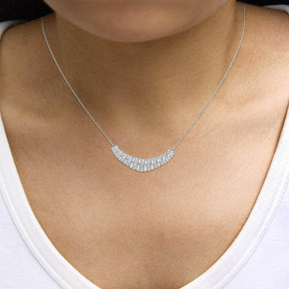 Close-up front angle of a white necklace with a crescent-shaped pendant featuring alternating smooth and pave set white gemstones, shown worn on a model.