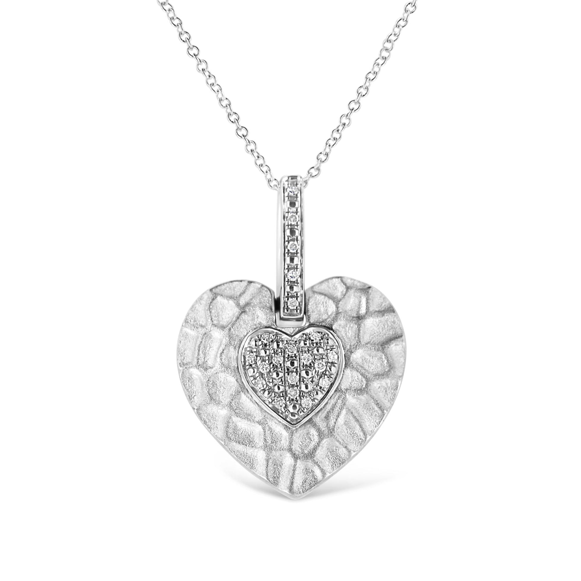 Front view of a white metal heart-shaped necklace pendant with a textured surface and a smaller heart in the center set with round white gemstones in a pave setting.