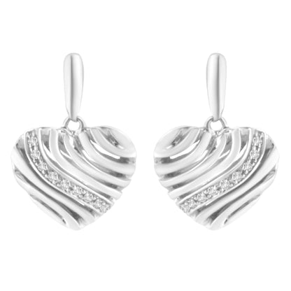 Front view of white metal heart-shaped earrings with diagonal ridges and a curved line of round white gemstones in a pave setting.
