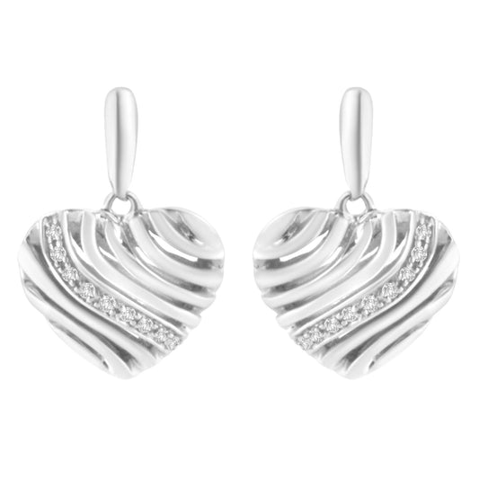 Front view of white metal heart-shaped earrings with diagonal ridges and a curved line of round white gemstones in a pave setting.