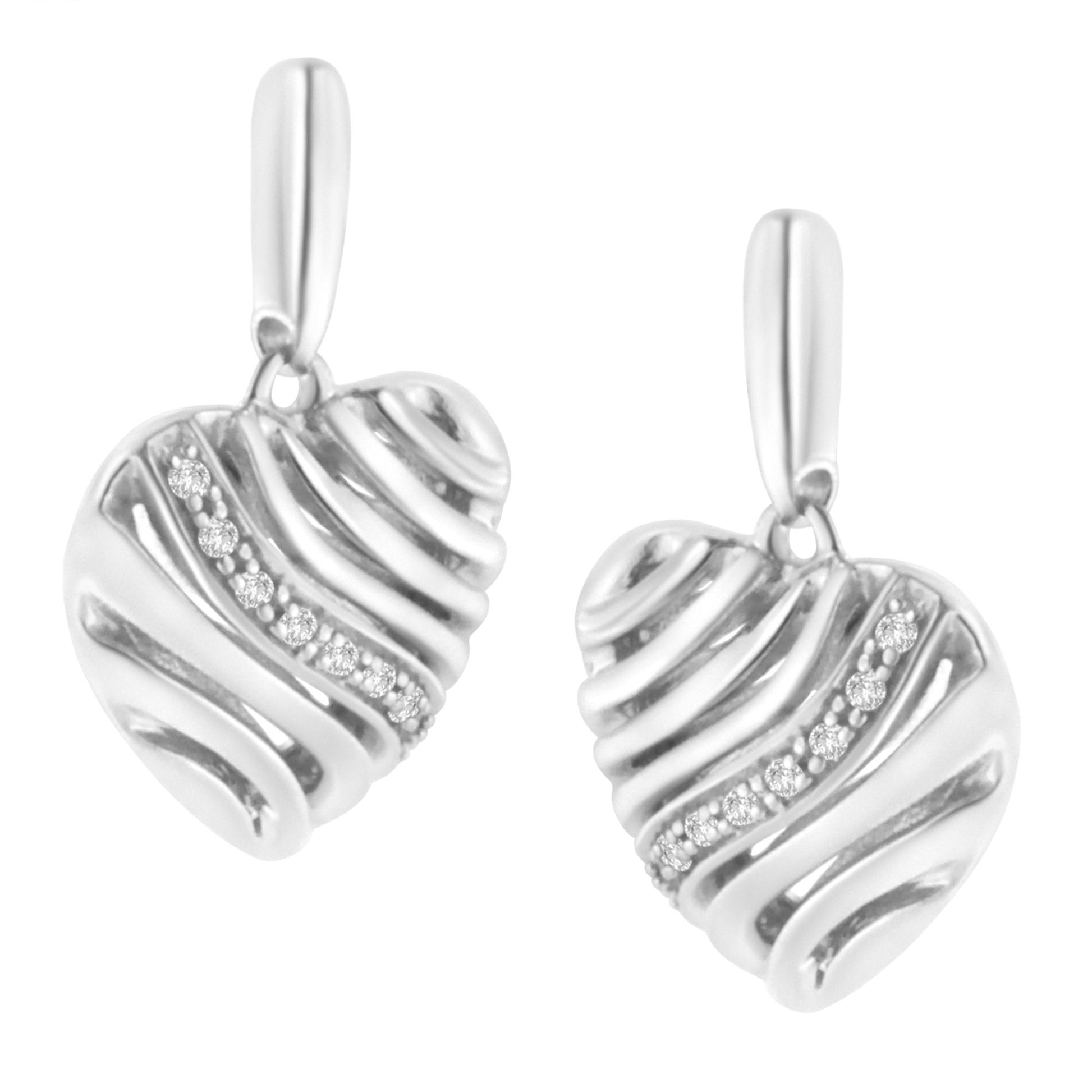 Front angle view of a pair of white metal heart-shaped earrings with wavy detailing and a curved line of pave-set round white gemstones.