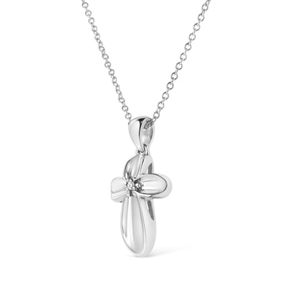 Front angled view of a white metal cross-shaped necklace pendant with a round white gemstone in a prong setting at the center, hanging from a chain.