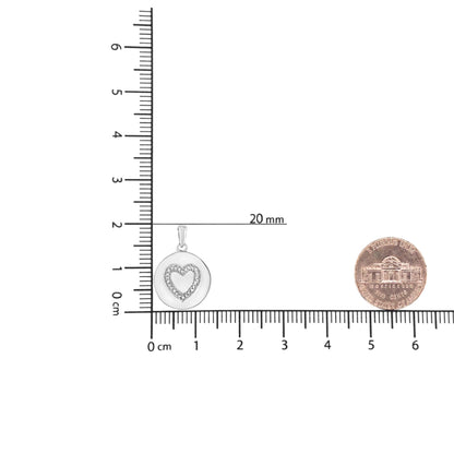 Front view of a white round necklace pendant with a heart-shaped hollow center outlined by small round white gemstones, placed on a ruler and scale for size reference.