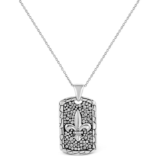 Front facing shot of a white metal necklace with a rectangular textured pendant featuring a central fleur-de-lis design accented with a row of round white gemstones in invisible setting.