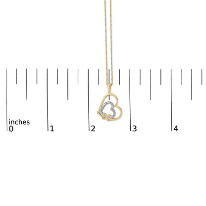 Yellow metal necklace with overlapping heart pendant, one heart outlined with white gemstones in pave setting, shown on a scale, front view.