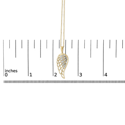 Close-up front angle of a yellow metal necklace pendant with a wing-shaped design featuring multiple white gemstones in a pave setting, shown on a measurement scale.
