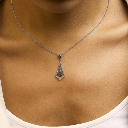 Close-up front view of a white metal necklace with black gemstones in pave setting on a model's neck. The necklace features a geometric pendant with two connected diamond-shaped sections.