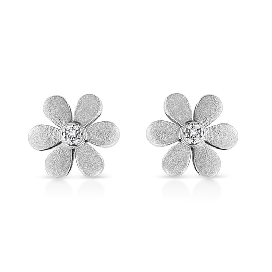 Pair of white metal flower-shaped earrings with textured petals and round white gemstones in the center, shown from a front angle on a white background.