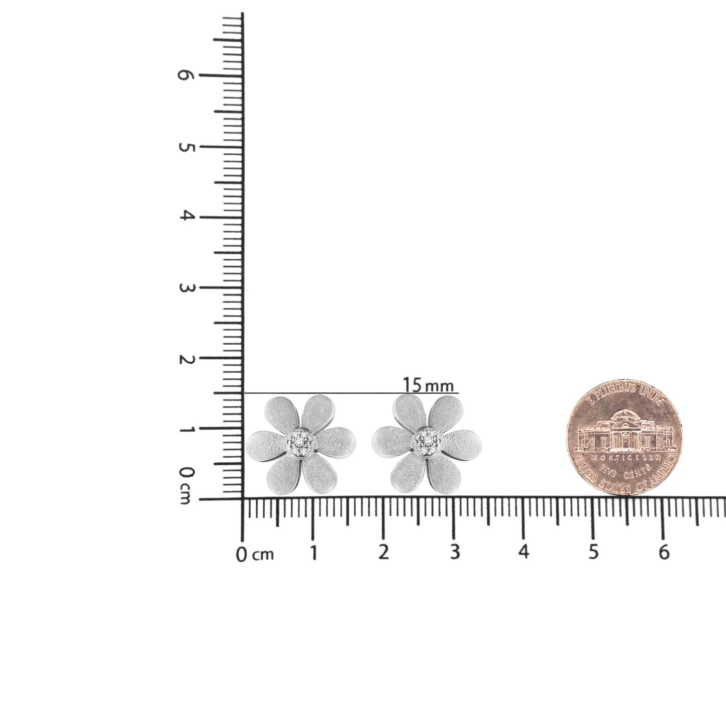 Pair of white metal flower-shaped earrings with round white gemstones in the center, shown from front on a ruler for size reference.