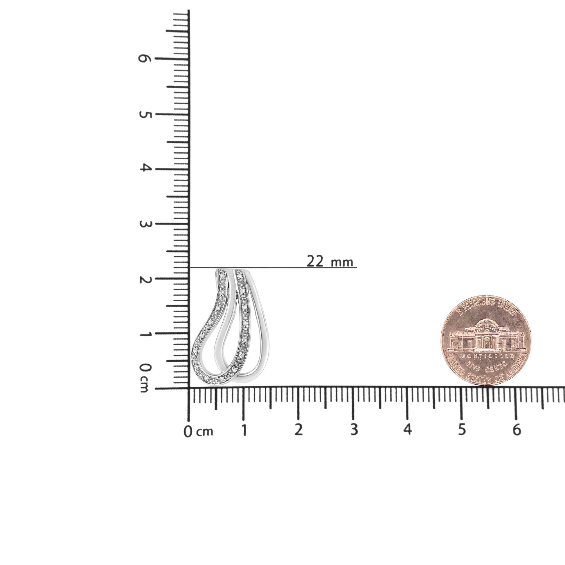 White metal necklace pendant with curved design featuring pave-set round white gemstones, shown on a ruler for size reference from a top-down angle.