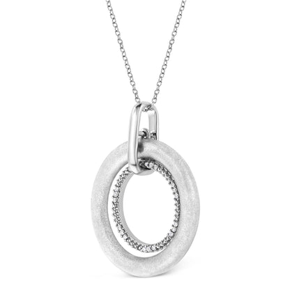 Close-up front angle of a white metal necklace featuring two interlocking circular pendants, the smaller inner circle adorned with round white gemstones in prong settings.