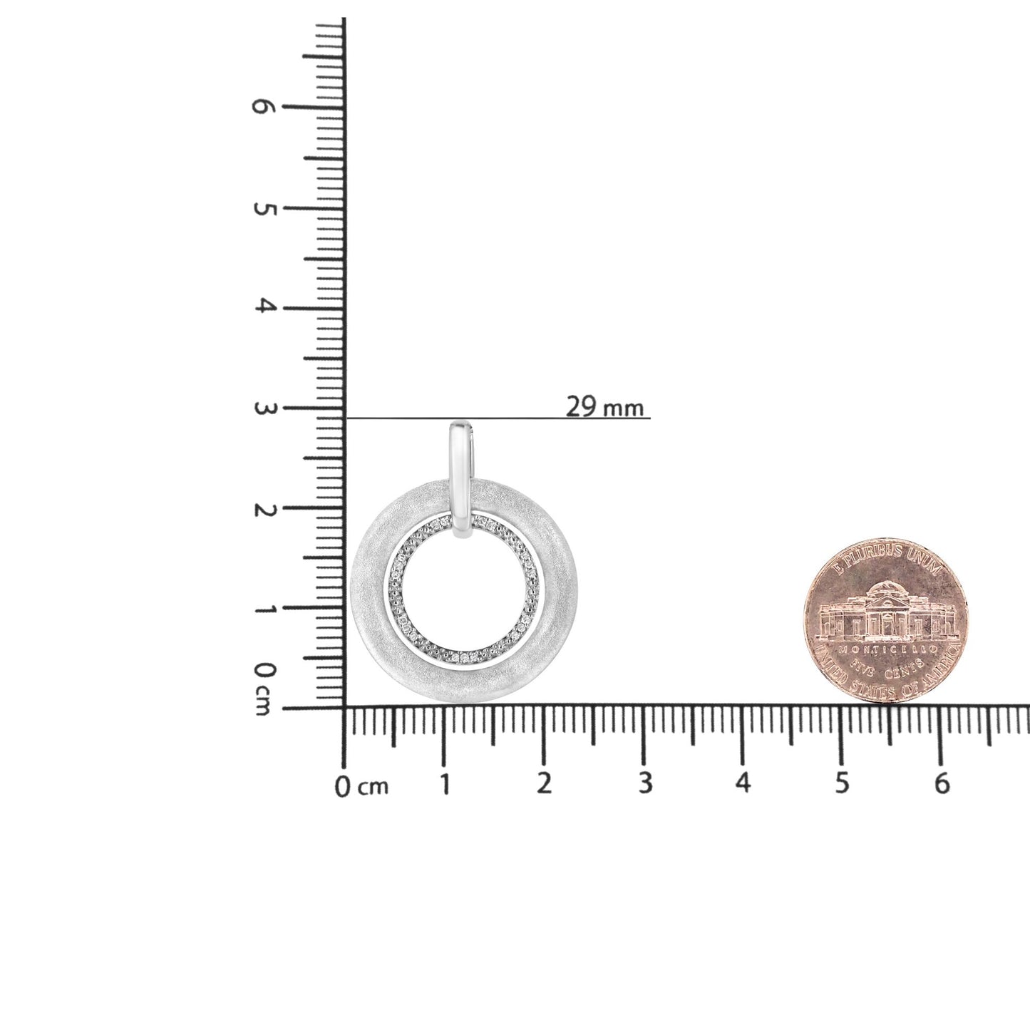 Top-down view of a white circular pendant necklace with an outer matte ring and an inner ring set with round white gemstones in prong settings, shown on a ruler and next to a coin for size reference.