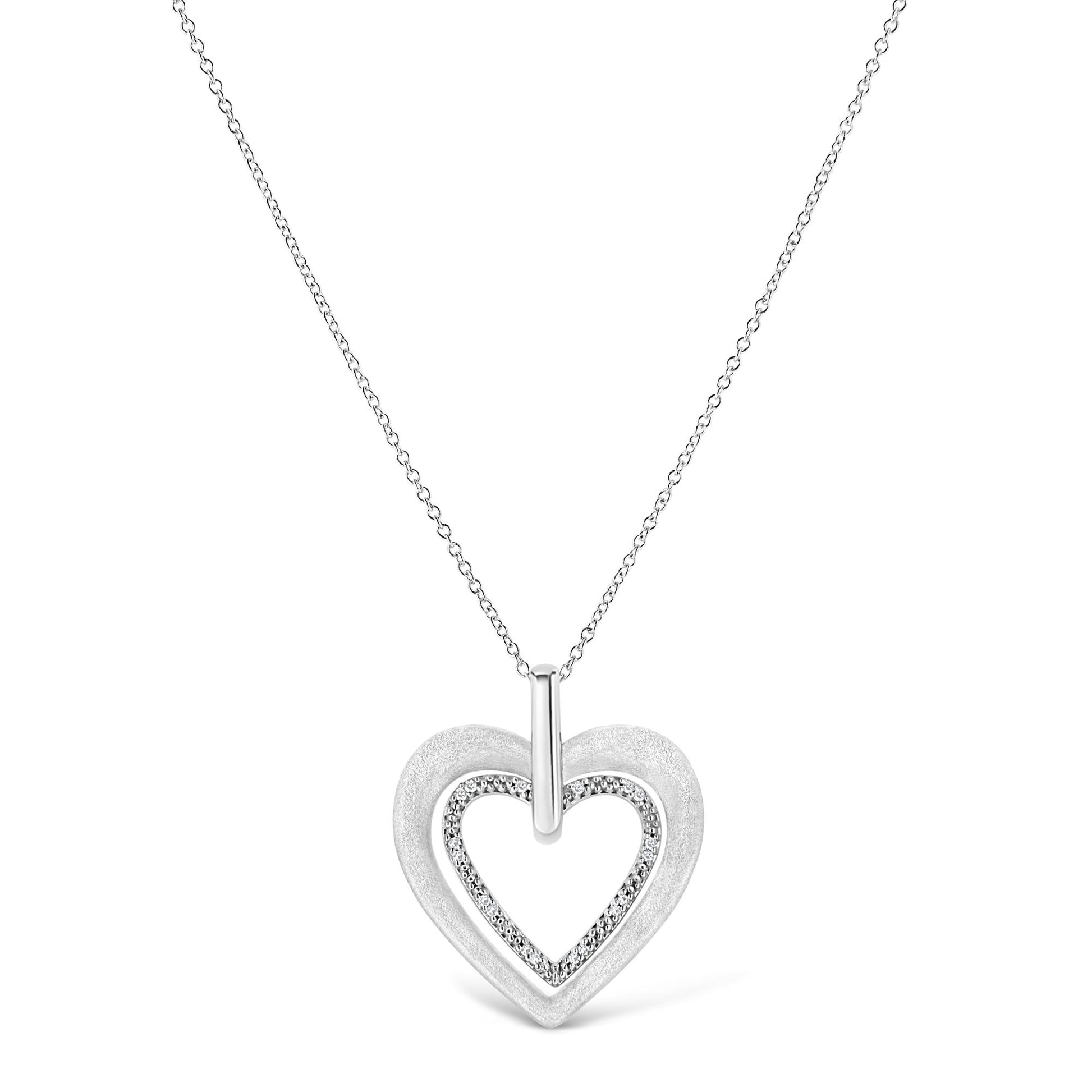 Front view of white metal heart-shaped necklace pendant with inner heart outlined by round prong-set white gemstones on a chain.