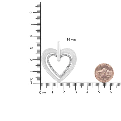 Top-down view of a white heart-shaped necklace pendant with round white gemstones in prong settings, shown on a ruler and next to a coin for size reference.