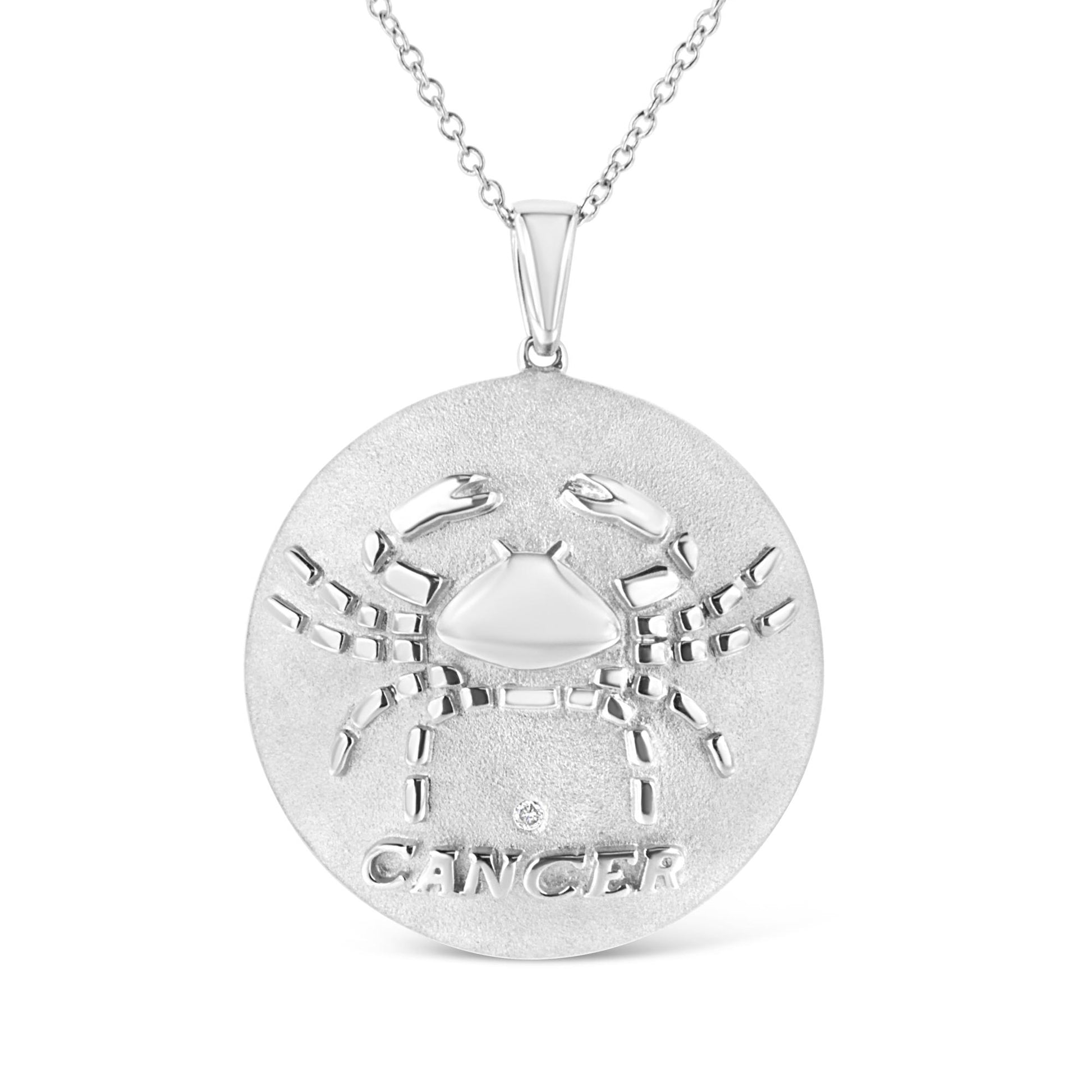Front view of a white metal round necklace pendant featuring a raised crab design with the word 'CANCER' and a small round brownish gemstone below the crab, on a white chain.