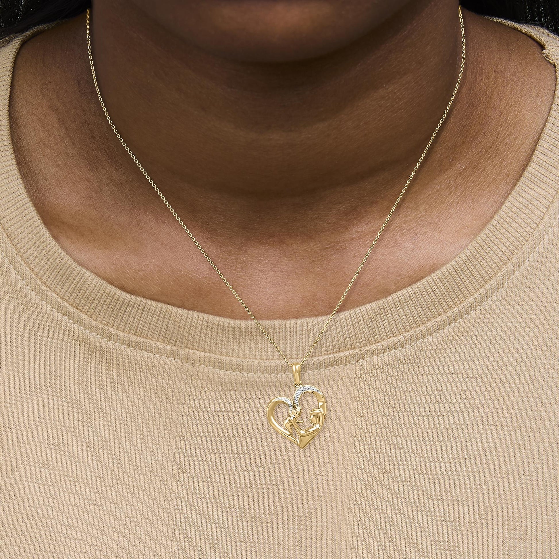 Close-up front view of a yellow metal necklace with a heart-shaped pendant featuring pave-set white gemstones, shown worn on a model.