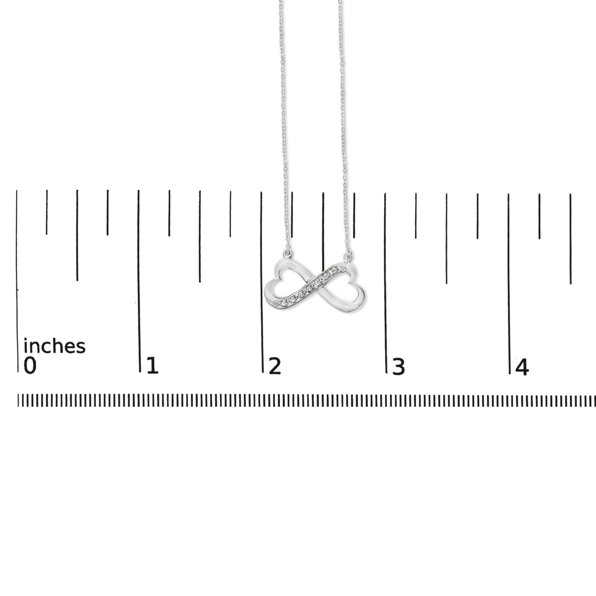 White metal necklace with an infinity heart pendant featuring a pave setting of round white gemstones, shown on a scale with a front view.