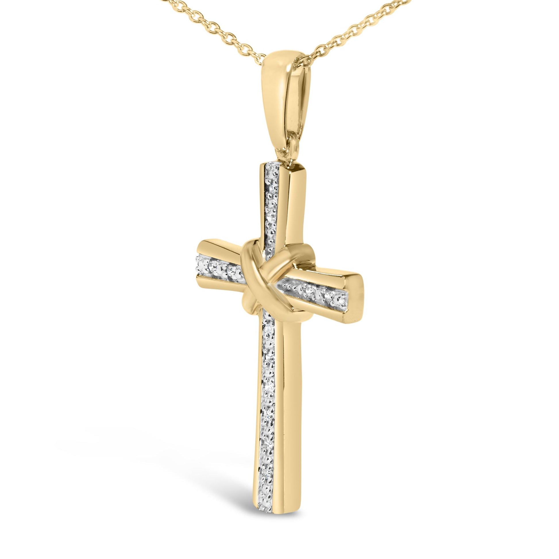 Close-up front view of a yellow metal necklace pendant in the shape of a cross with a knot in the center, featuring vertical and horizontal rows of small white gemstones in pave setting.