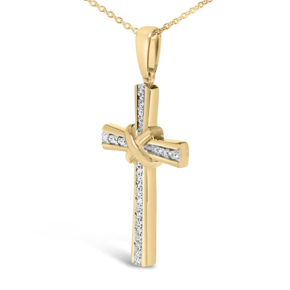 Close-up front view of a yellow metal necklace pendant in the shape of a cross with a knot in the center, featuring vertical and horizontal rows of small white gemstones in pave setting.