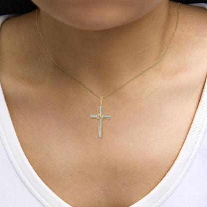 Yellow metal necklace with cross pendant featuring white gemstones in a pave setting, shown worn on a model, close-up angle.
