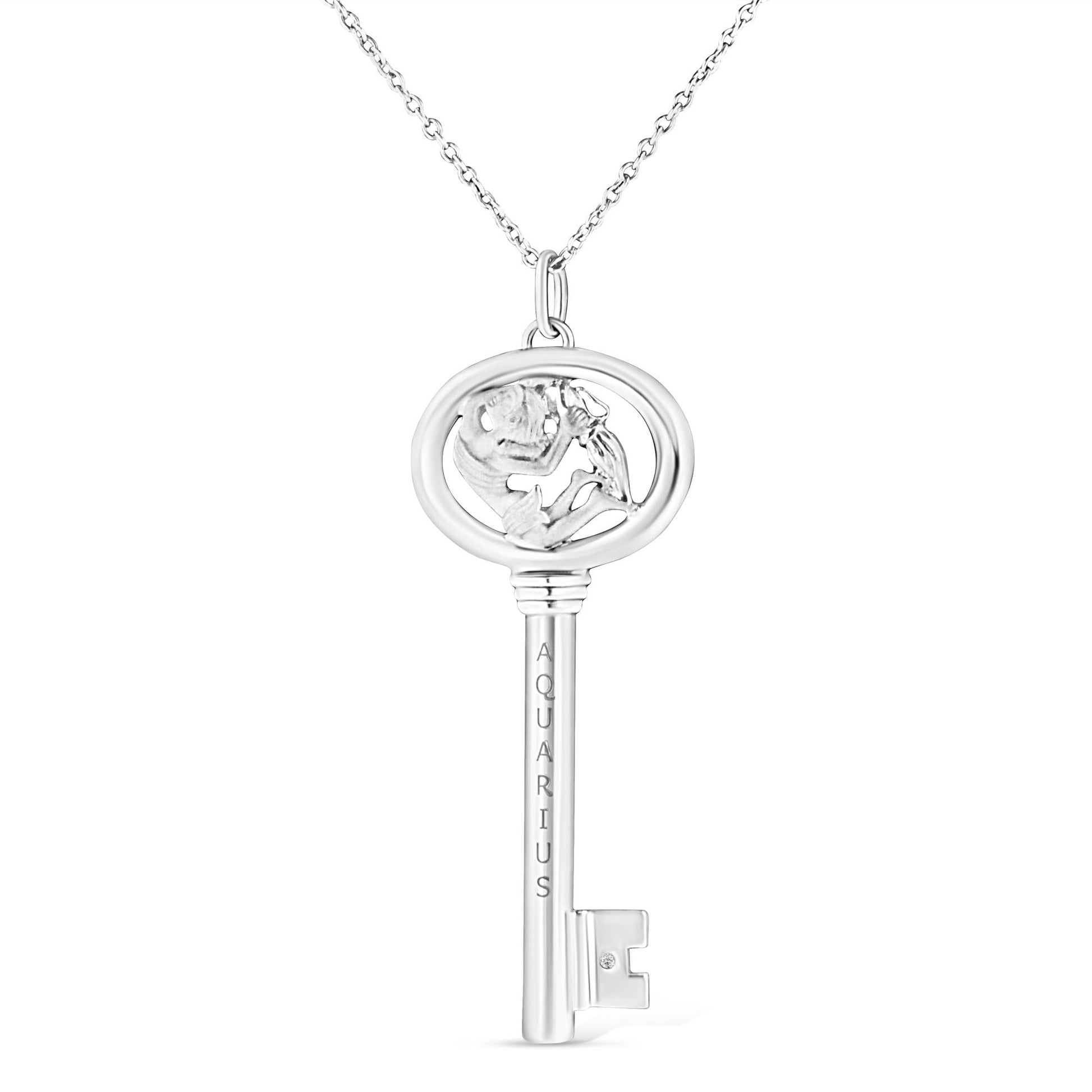 Front view of white metal key-shaped necklace pendant with Aquarius engraving and round bezel-set brownish gemstone near the teeth of the key.