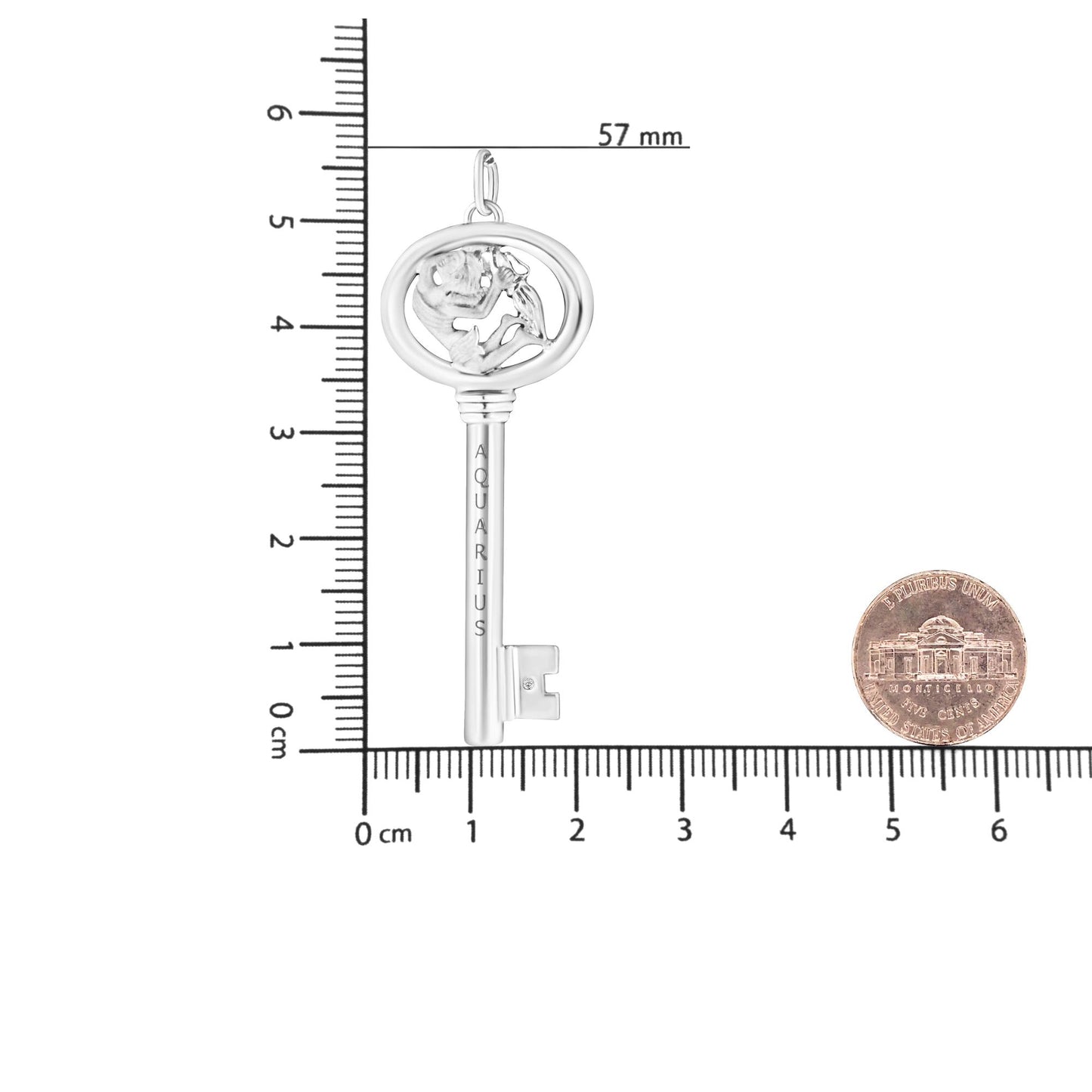 White metal necklace pendant shaped like a key with an oval top featuring a figure and a small round brownish gemstone in bezel setting on the shaft, shown flat on a ruler and beside a coin for size reference, front view.