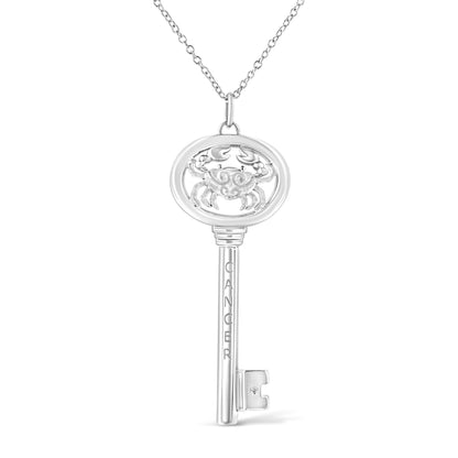 Front-facing white metal key-shaped necklace pendant with an engraved crab design and a small brownish round gemstone in bezel setting near the key bit, shown on a white background.