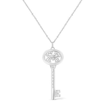 Front view of a white metal key-shaped necklace pendant with a crab design at the top oval section and a round brownish bezel-set gemstone near the bottom.