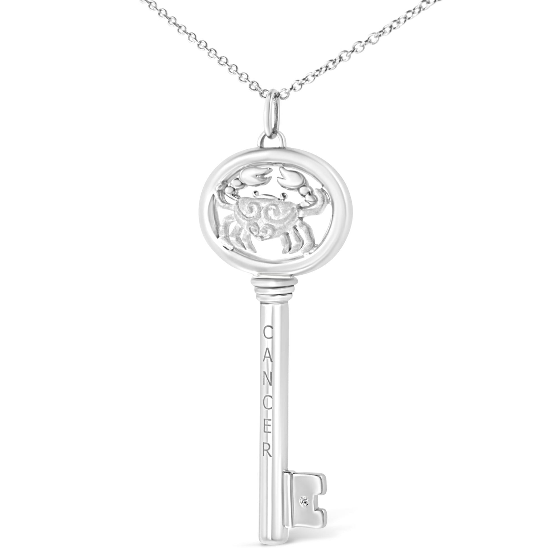 Front view of white key-shaped necklace pendant with crab design, 'CANCER' engraved vertically, and small brownish round gemstone in bezel setting near the bottom, suspended on a chain.