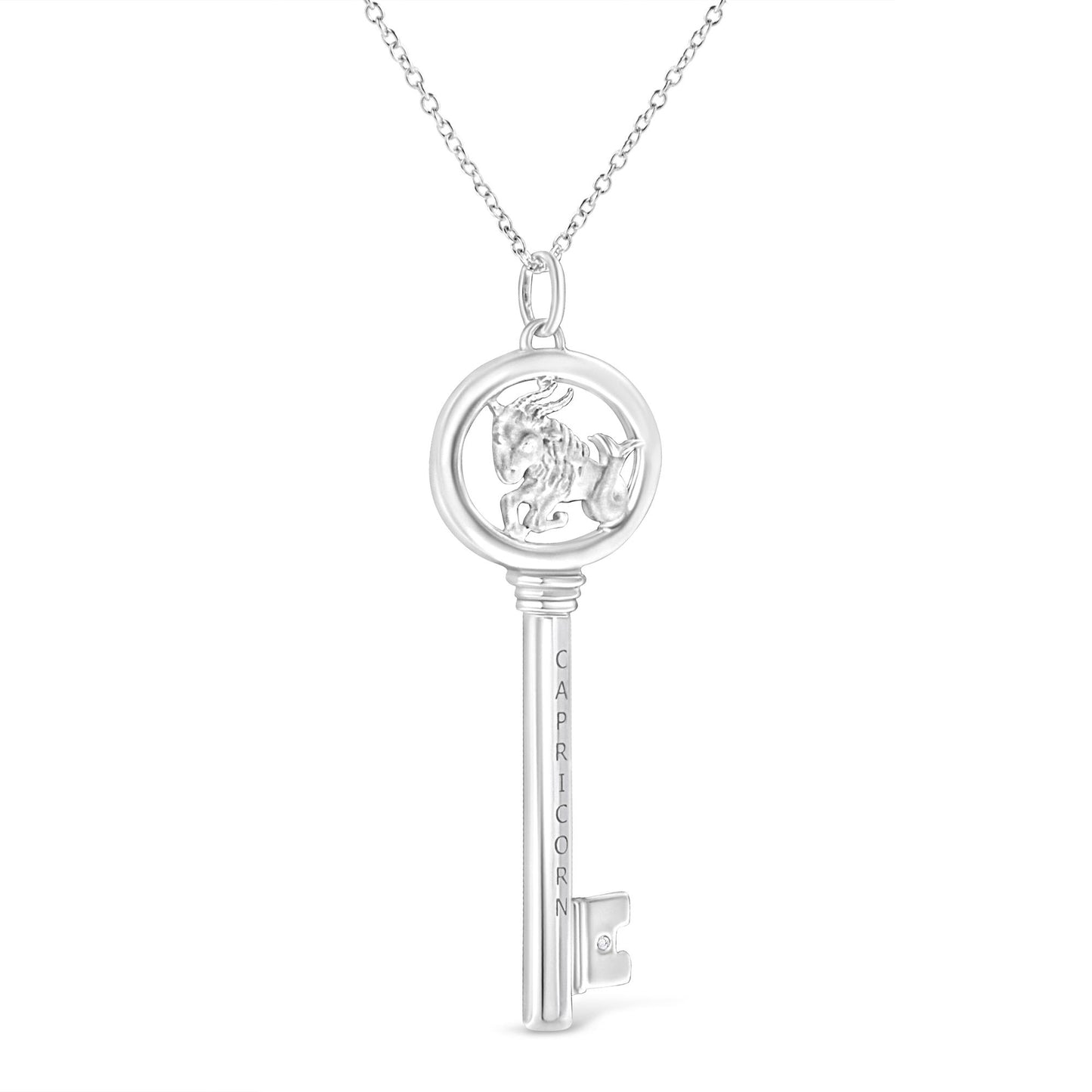 Front-facing shot of a white metal key-shaped necklace pendant with a Capricorn symbol inside the circular top and a small round brownish gemstone in a bezel setting near the bottom.