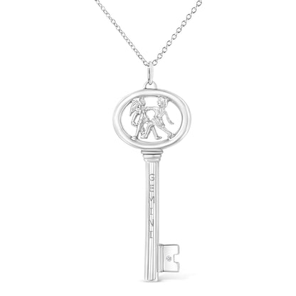 Front-facing white metal key-shaped necklace pendant with two children figures inside the oval top and a small round brownish gemstone in bezel setting on the key bit.