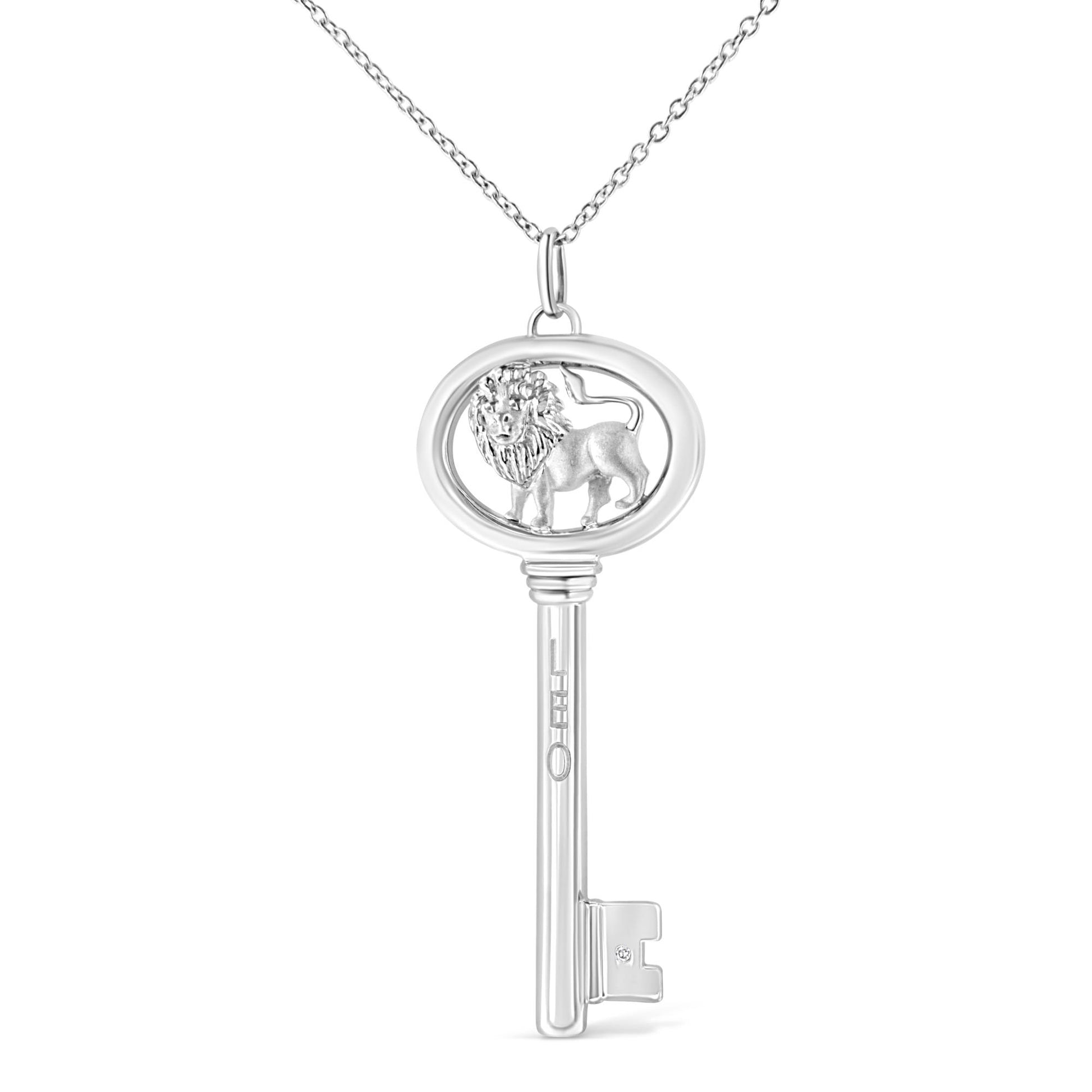 Front view of a white metal key-shaped necklace pendant with an oval top featuring a lion design and a small round brownish gemstone in a bezel setting near the bottom.
