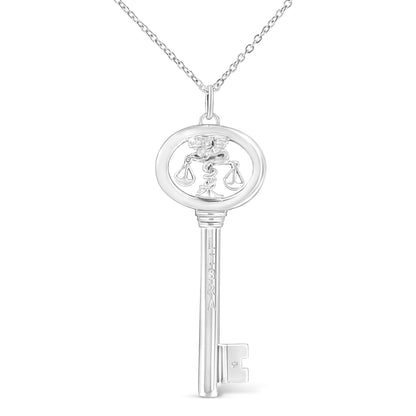Front view of a white metal key-shaped necklace pendant featuring a round bezel-set brownish gemstone near the bottom and a design of scales within an oval at the top, hanging from a chain.