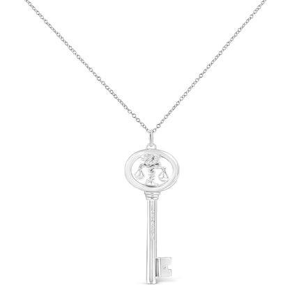 Front-facing image of a white metal key-shaped necklace pendant with a zodiac scales symbol in the oval top part and a small brownish round gemstone near the bottom of the key.