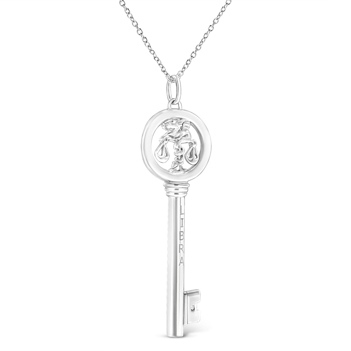 Front view of a white metal key-shaped necklace pendant with a Libra symbol inside the circular top and a single brownish round gemstone in bezel setting near the bottom end, hanging from a chain.