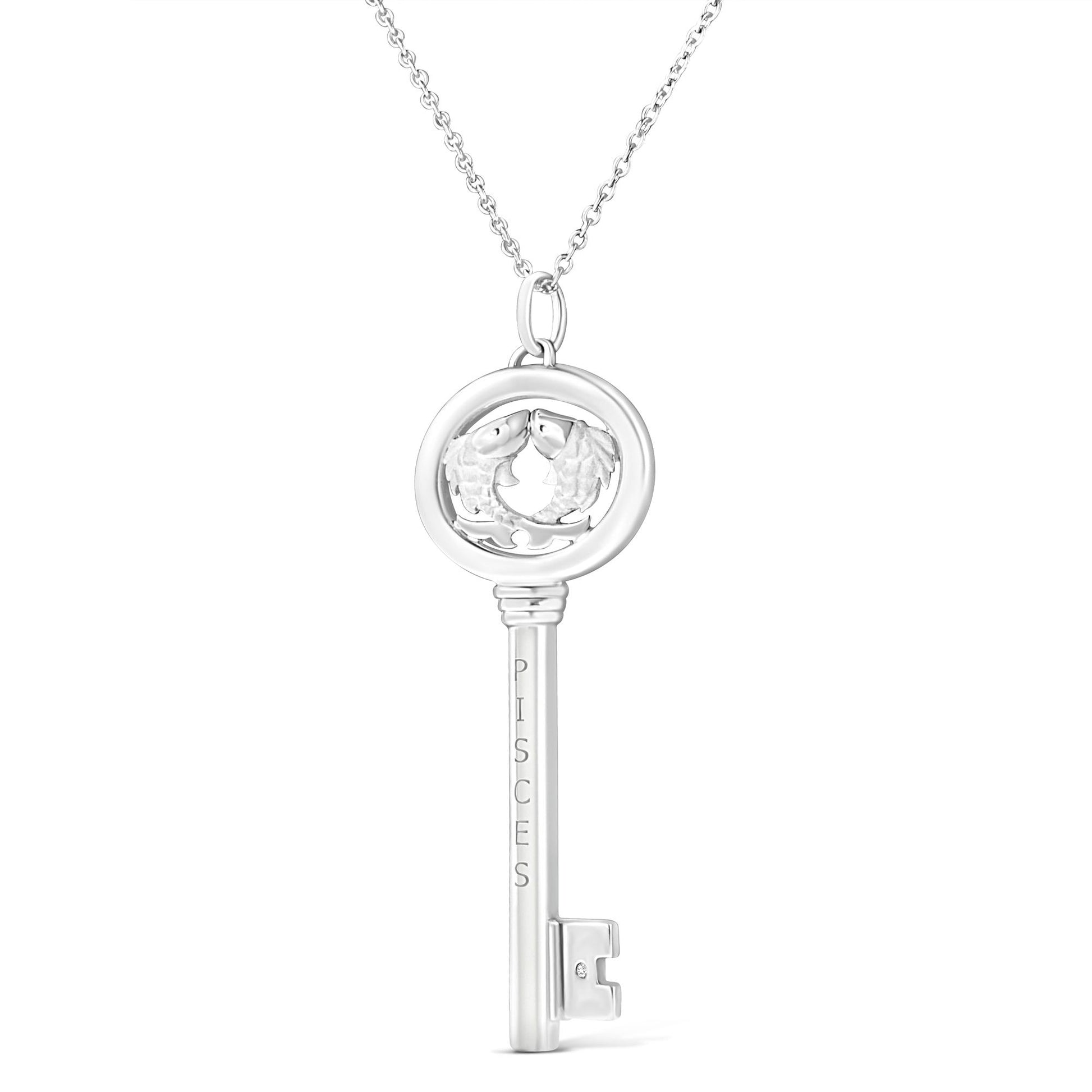 Front-facing image of a white metal key-shaped necklace pendant featuring two fish inside a circular top and a small brownish round gemstone near the bottom.
