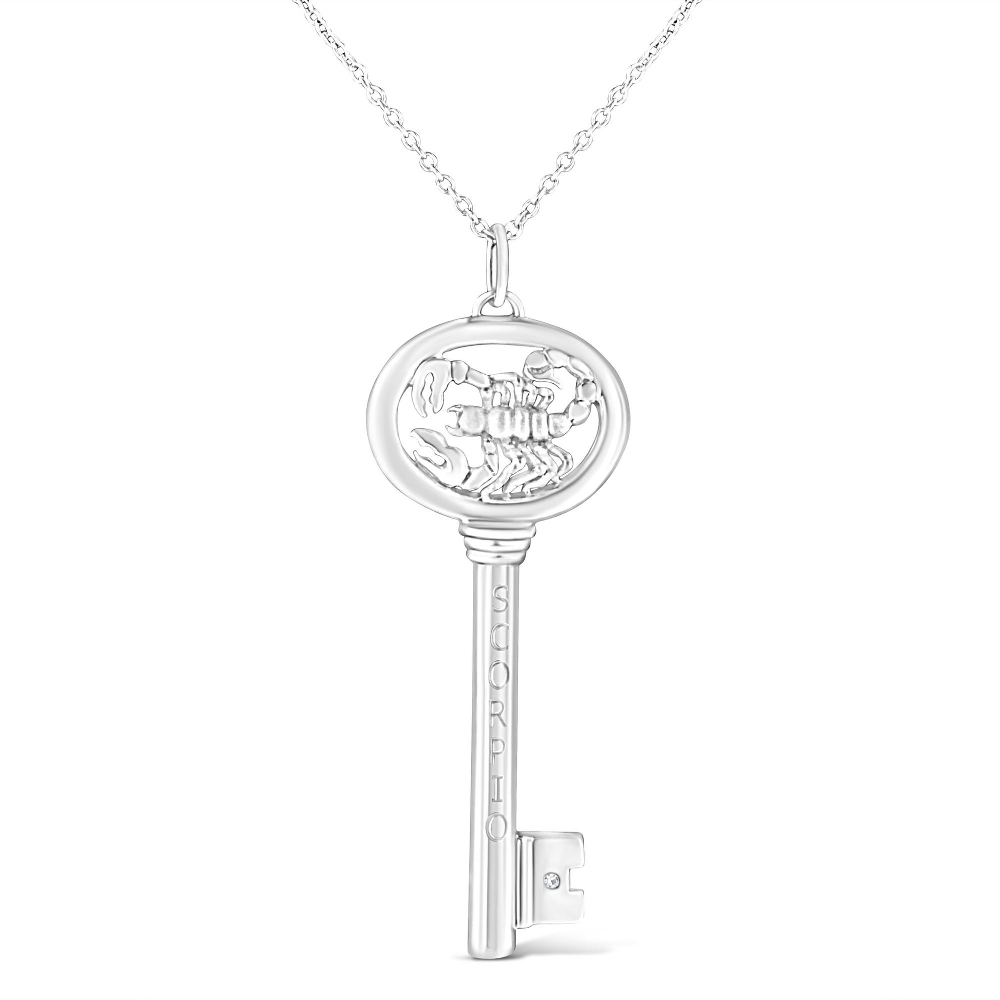 Front facing shot of a white metal key-shaped necklace pendant with a scorpion design inside the round top and one brownish round gemstone in a bezel setting near the bottom.