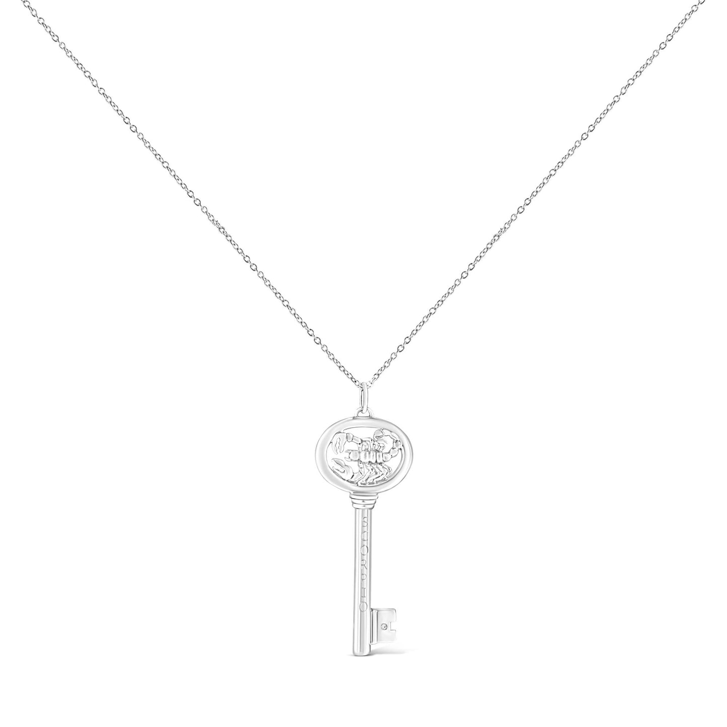 Front view of a white metal key-shaped necklace pendant with a round bezel-set brownish gemstone on the key bit, shown on a white background.