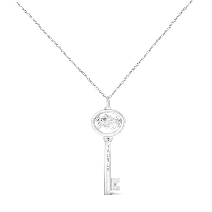 White metal key-shaped necklace pendant with an oval top featuring a raised bull figure and engraved 'TAURUS' on the shaft, with a small brownish round gemstone set near the key bit, shown in a front-facing view.