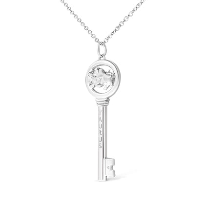 White metal key-shaped necklace pendant with Taurus engraving and round bezel-set brownish gemstone, front-facing angle.