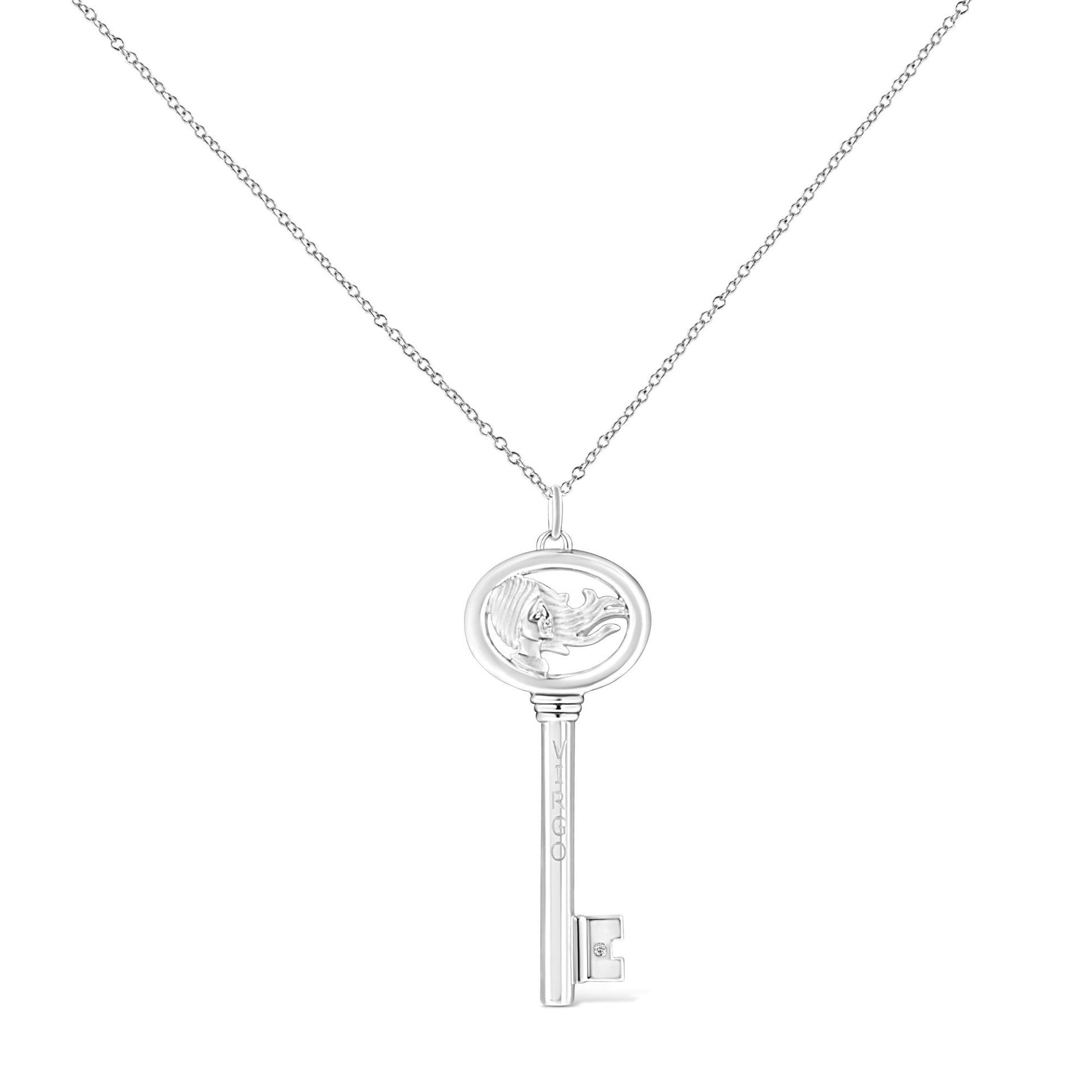Front view of a white metal key-shaped necklace pendant with an embossed female figure in the oval top section and a single bezel-set round brownish gemstone near the bottom.