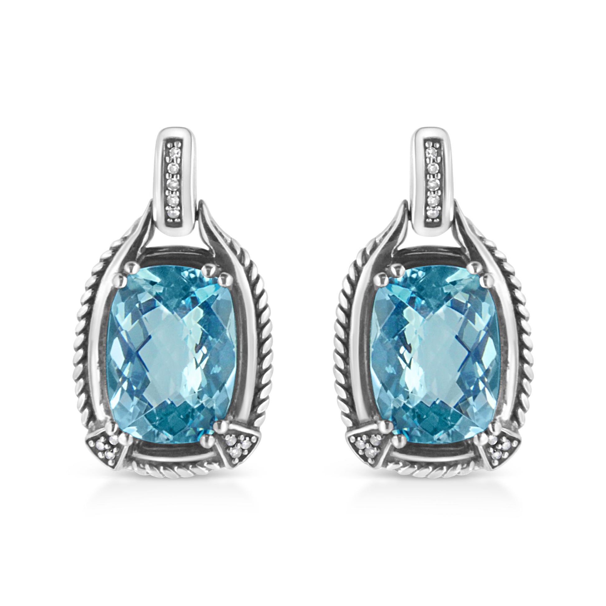 Front view of white metal earrings featuring cushion-shaped blue gemstones in prong settings surrounded by round white gemstones in invisible settings.