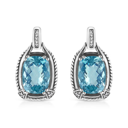 Front view of white metal earrings featuring cushion-shaped blue gemstones in prong settings surrounded by round white gemstones in invisible settings.