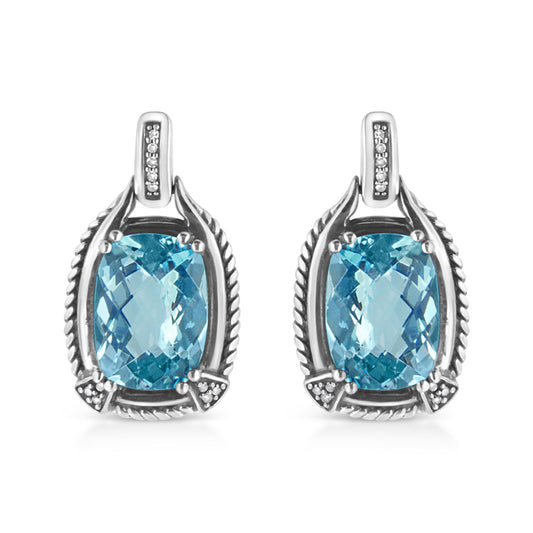 Front view of white metal earrings featuring cushion-shaped blue gemstones in prong settings surrounded by round white gemstones in invisible settings.