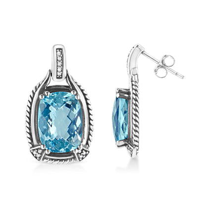Pair of white metal earrings with cushion-shaped blue gemstones in prong settings, surrounded by round white gemstones in invisible settings; one earring shown front-facing and the other in profile angle.