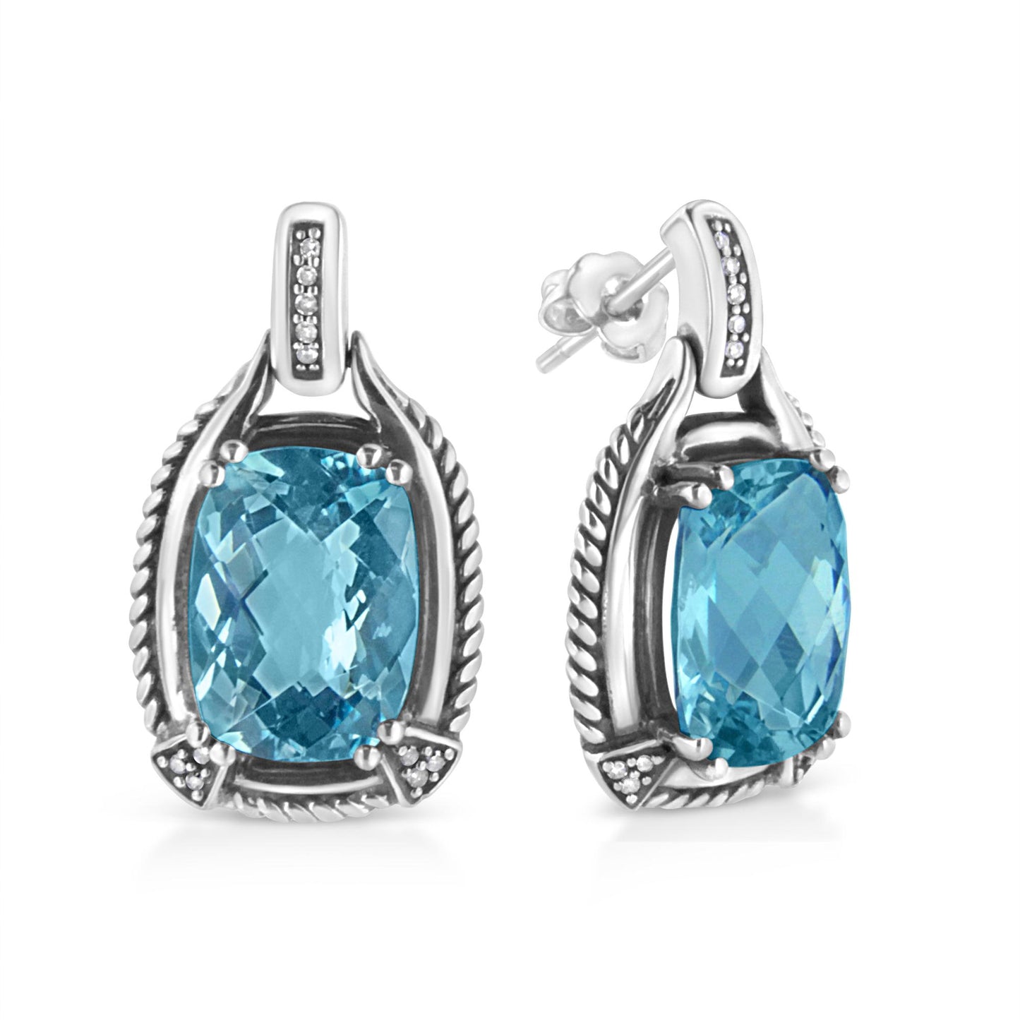 Front and side angled view of white metal earrings with cushion-shaped blue gemstones prong-set in the center, surrounded by white round gemstones in an invisible setting.